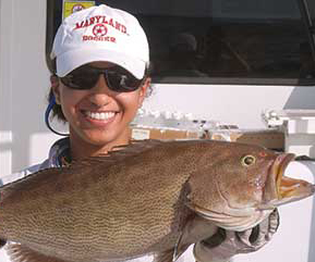 Samara holding up a fish on a boat.