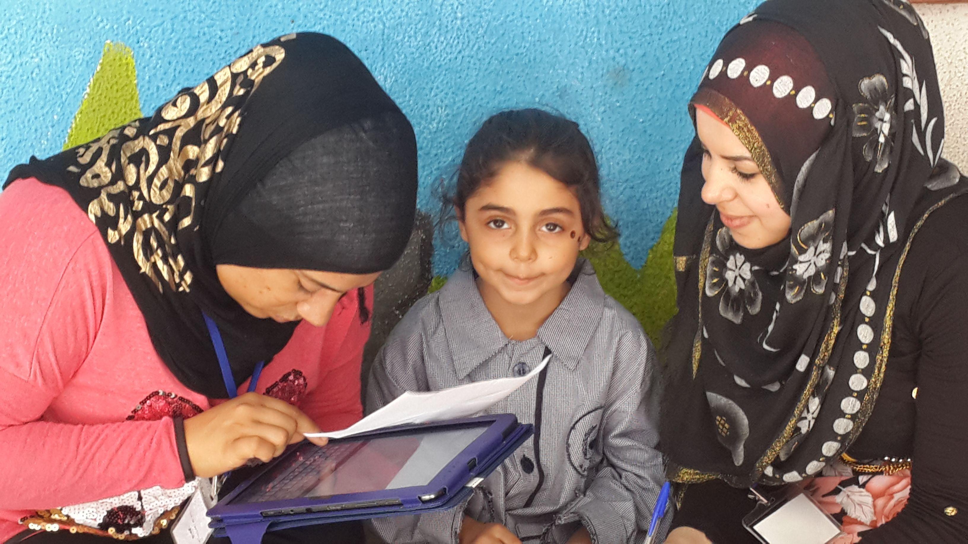 Palestinian women enrolling a child to receive healthy meals